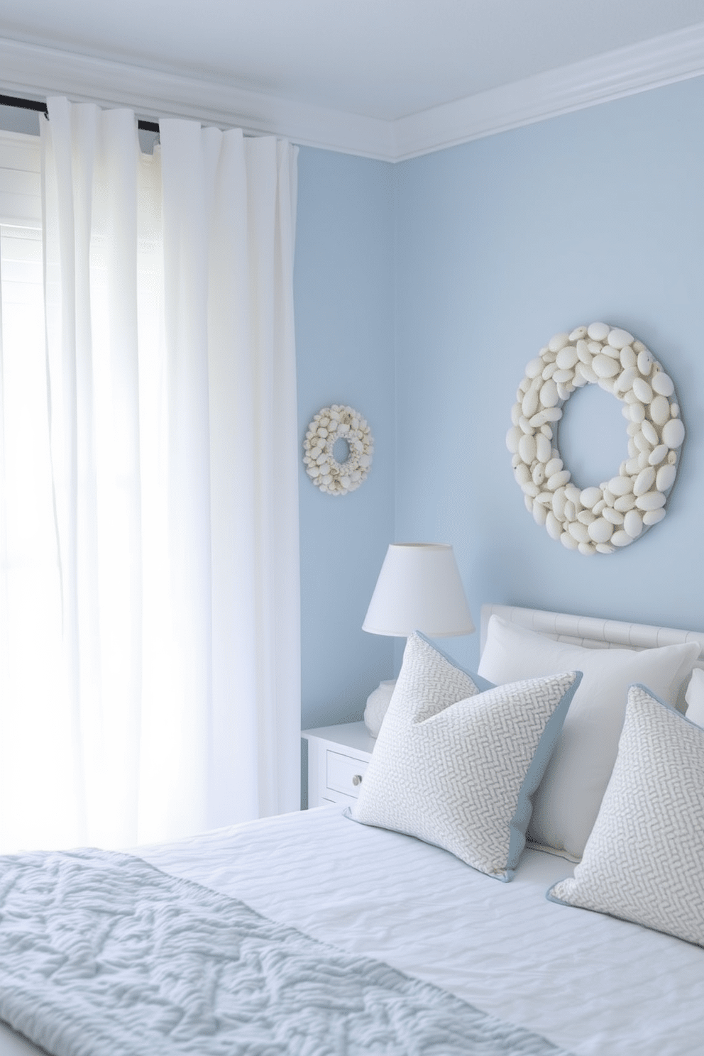 A coastal bedroom featuring charming shell wreaths as wall art. The room has soft blue walls and natural light streaming through sheer white curtains, creating a serene atmosphere.