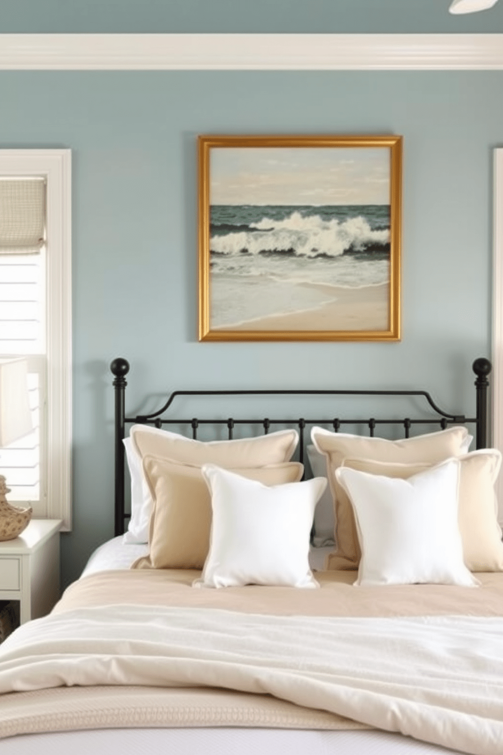 A serene coastal bedroom featuring ocean-themed artwork above the bed. The walls are painted in soft blue tones, and the bedding incorporates sandy beige and crisp white colors.