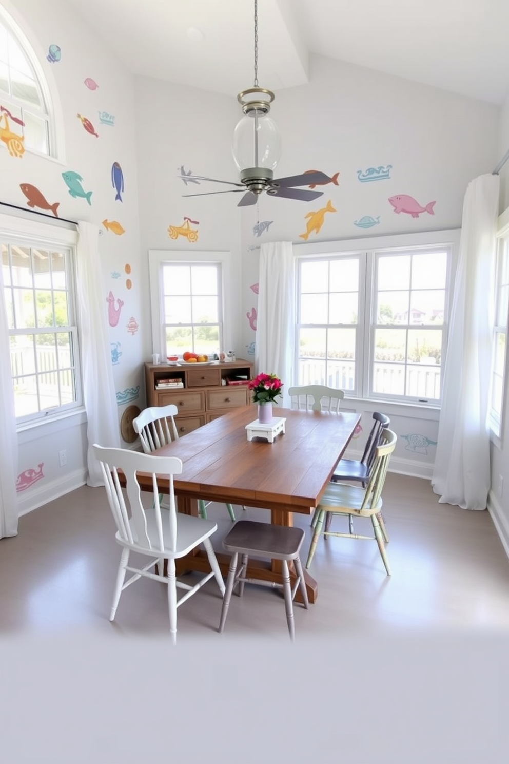 Beach inspired wall decals create a vibrant and playful atmosphere in the dining room. The walls are adorned with colorful ocean-themed designs, enhancing the coastal vibe of the space. The dining area features a rustic wooden table surrounded by mismatched chairs in soft pastel hues. Large windows allow natural light to flood the room, complemented by airy white curtains that sway gently in the breeze.