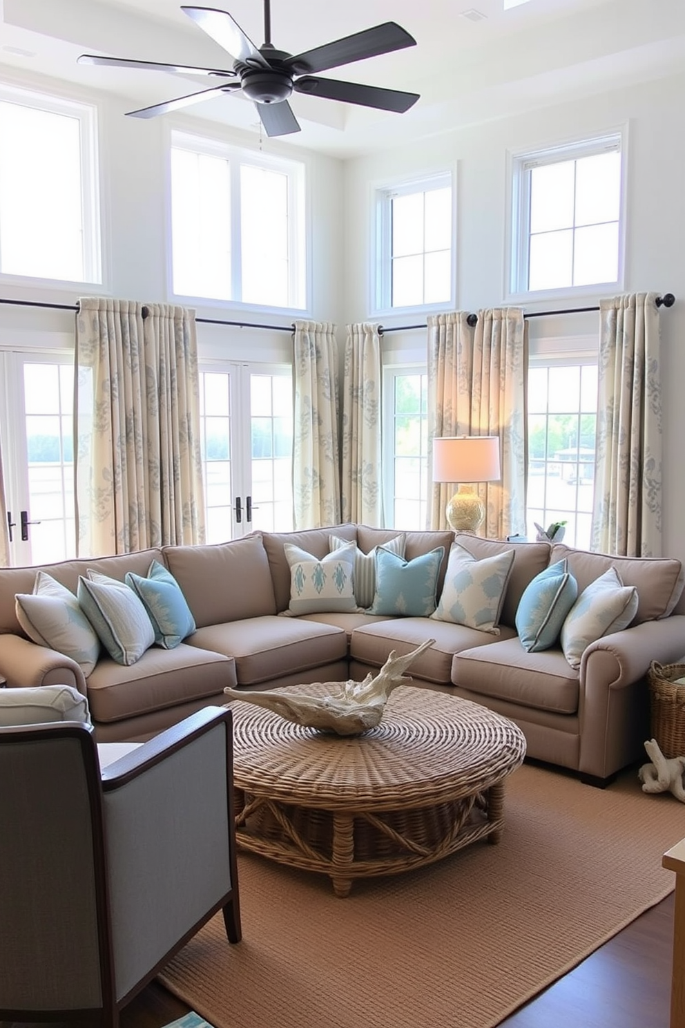 A coastal living room filled with natural light. The curtains and drapes feature beachy patterns in soft blues and sandy beige tones. A large, comfortable sectional sofa is adorned with throw pillows in ocean-inspired colors. The room is complemented by a woven coffee table and driftwood accents throughout.