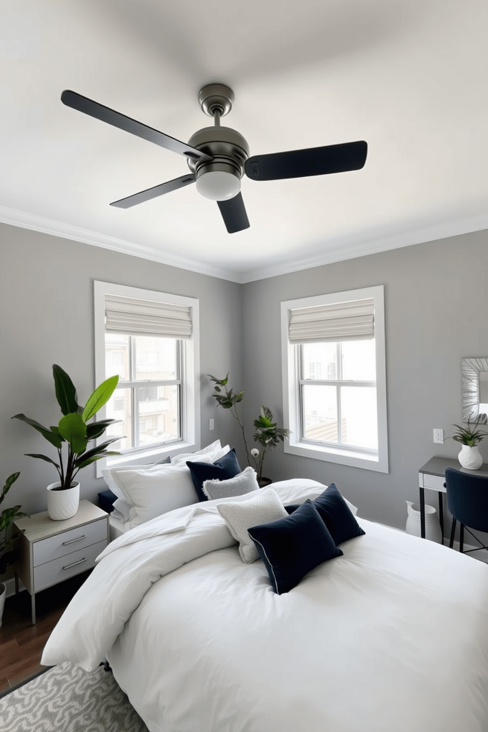 A cozy condo bedroom features a stylish ceiling fan that enhances airflow while adding a modern touch. The walls are painted in a soft gray, complemented by a plush bed adorned with layered white and navy bedding. Natural light filters through large windows, highlighting a sleek nightstand on one side and a minimalist desk on the other. The room is accented with indoor plants that bring a fresh vibe and a touch of greenery to the space.