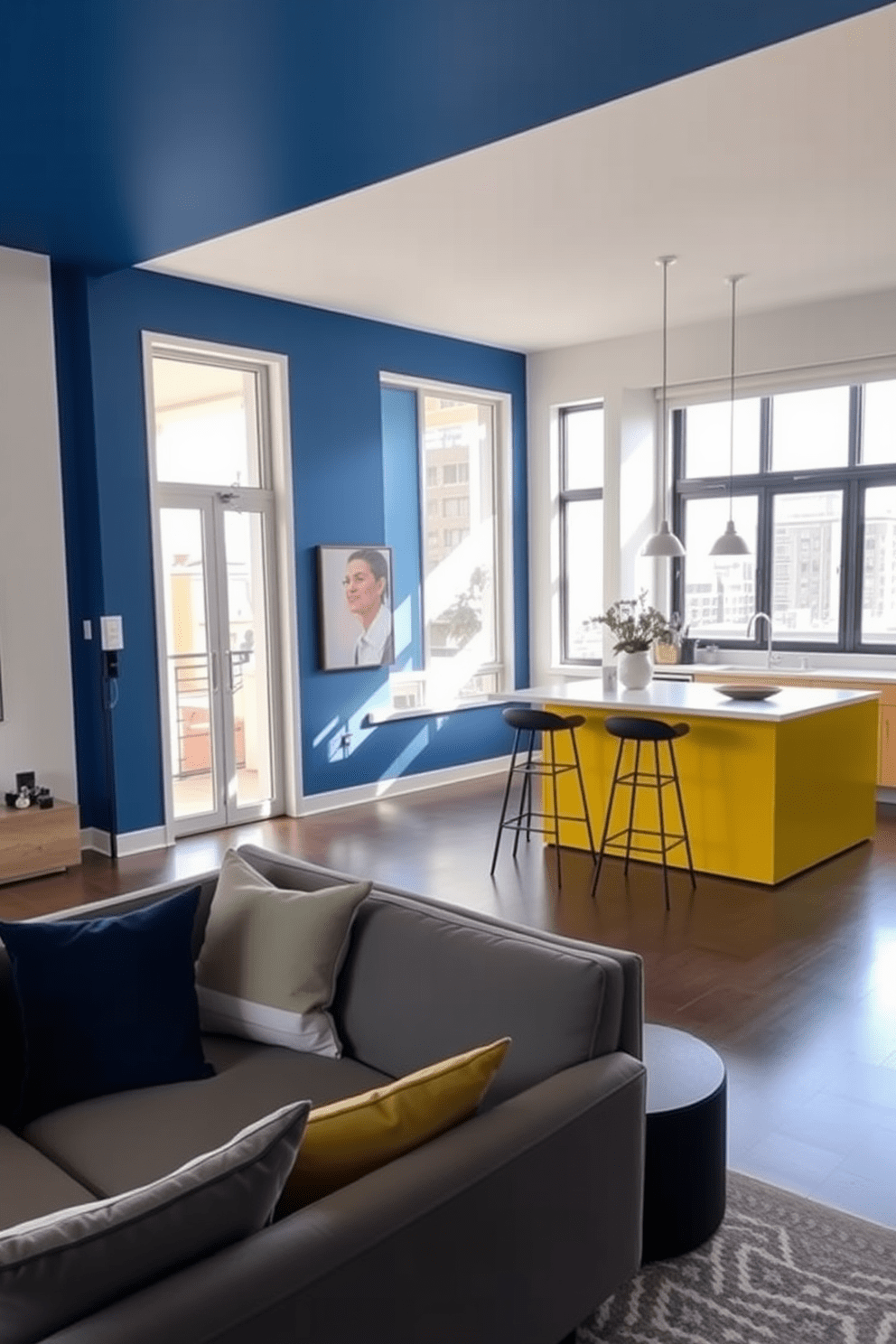 A contemporary apartment features distinct areas defined by bold color blocking. The living room showcases a striking blue accent wall, while the kitchen area is highlighted with a vibrant yellow island, creating a dynamic and inviting atmosphere. Soft neutral tones in the furniture complement the vivid colors, ensuring balance throughout the space. Large windows allow natural light to flood in, enhancing the overall brightness and warmth of the apartment.