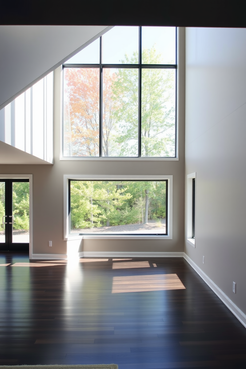 A contemporary basement design featuring floor-to-ceiling windows that flood the space with natural light. The walls are painted in a soft gray tone, and the flooring is a sleek dark hardwood that complements the modern aesthetic.