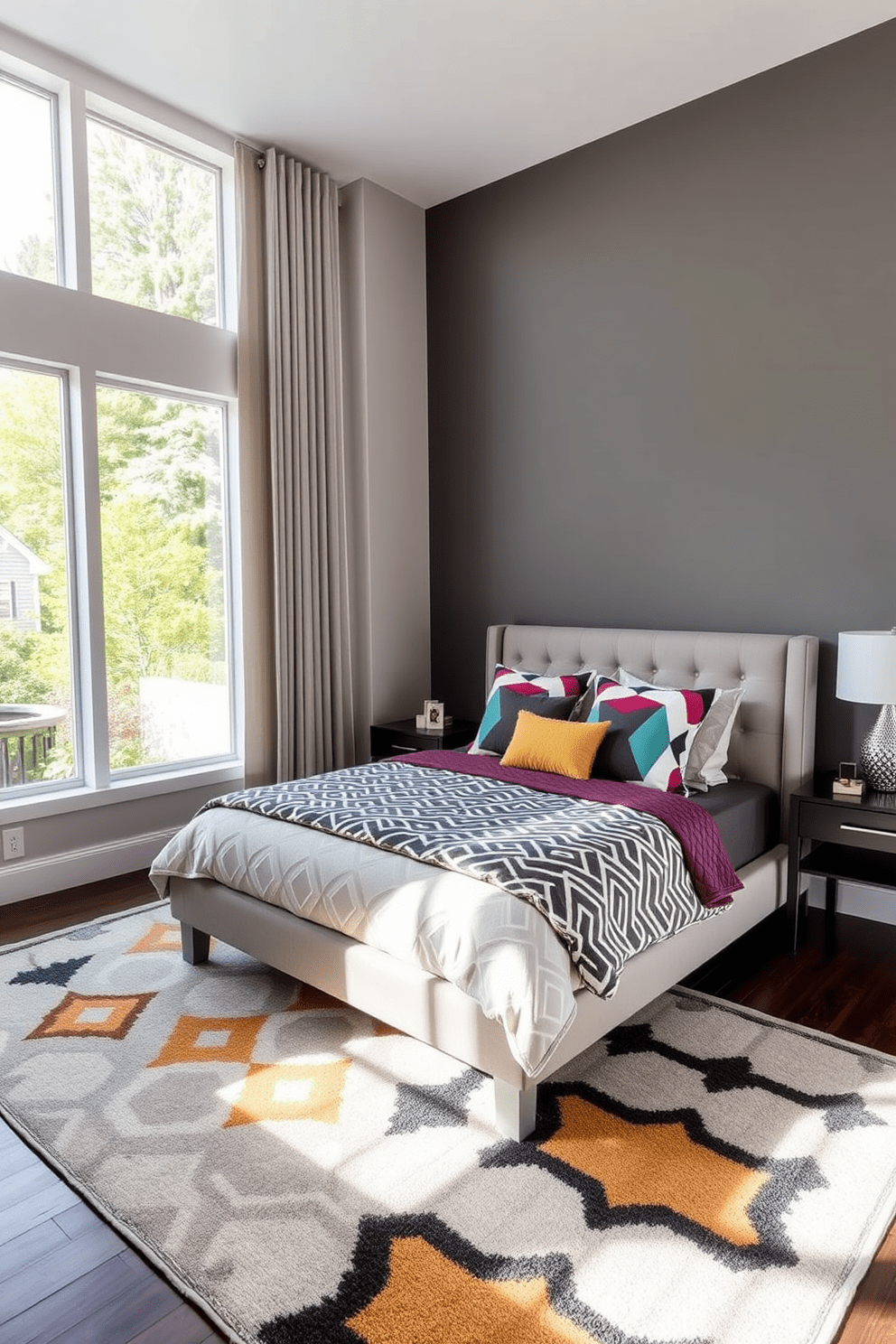 A contemporary bedroom featuring geometric patterns on the bedding and rugs. The walls are painted in a soft gray, and large windows allow natural light to flood the space. The bed has a low-profile frame with a plush headboard, adorned with colorful geometric throw pillows. A stylish area rug with bold patterns anchors the space, complementing the overall modern aesthetic.