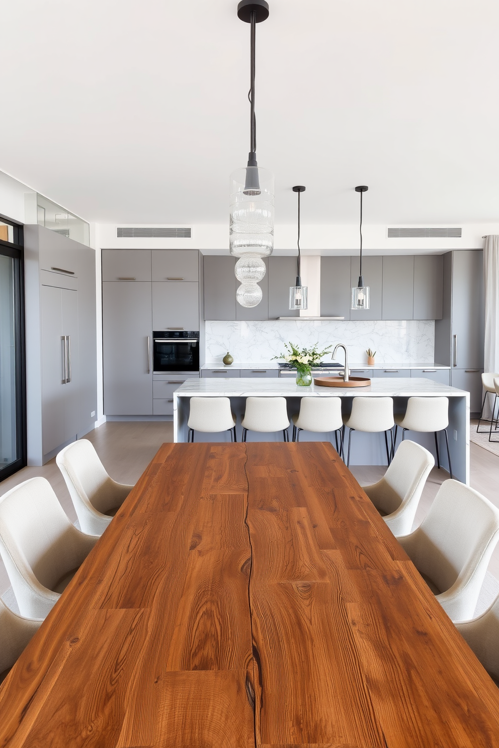 A spacious open concept dining and kitchen area seamlessly blends modern aesthetics with functionality. The dining table, crafted from reclaimed wood, is surrounded by sleek upholstered chairs in a neutral tone, creating an inviting atmosphere. In the kitchen, minimalist cabinetry in a soft gray complements a striking marble backsplash. Pendant lights hang gracefully above the island, illuminating the space and enhancing the contemporary design.