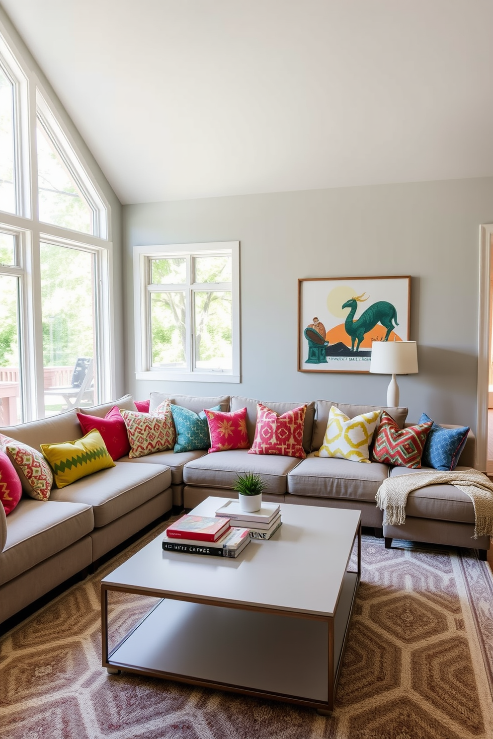 A contemporary family room features a cozy sectional sofa adorned with colorful throw pillows in various patterns and textures. The walls are painted in a soft gray tone, while a large area rug with geometric designs anchors the seating area. A sleek coffee table sits at the center, topped with decorative books and a small succulent. Large windows allow natural light to flood the space, enhancing the vibrant colors of the pillows and the overall inviting atmosphere.