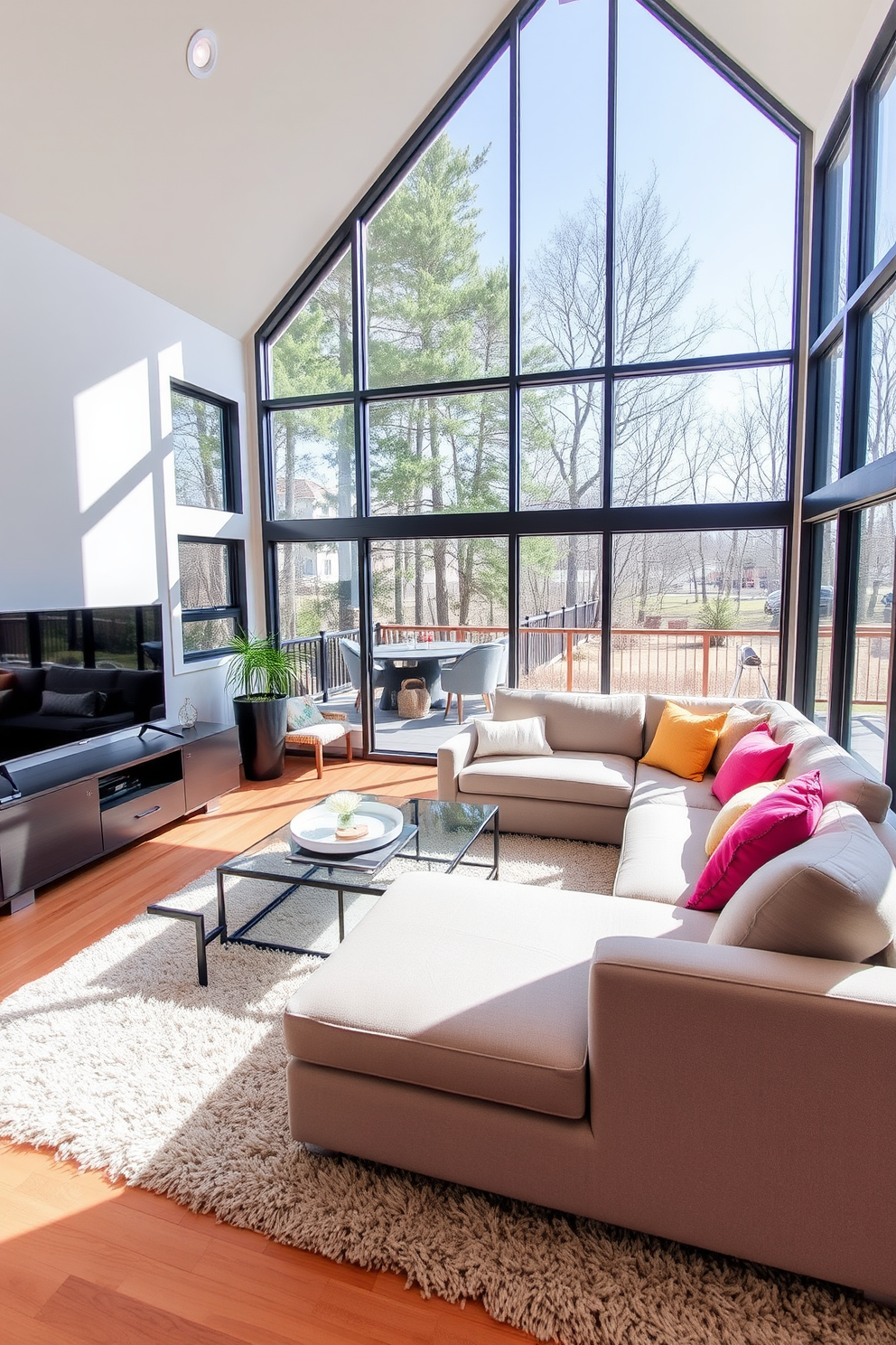 A contemporary family room with large windows that invite natural light and provide a seamless connection to the outdoors. The space features a comfortable sectional sofa in neutral tones, complemented by a sleek coffee table and vibrant accent pillows. A modern entertainment center is positioned against one wall, showcasing a flat-screen TV and stylish decor. The flooring is a warm hardwood, and a plush area rug anchors the seating arrangement, enhancing the inviting atmosphere.