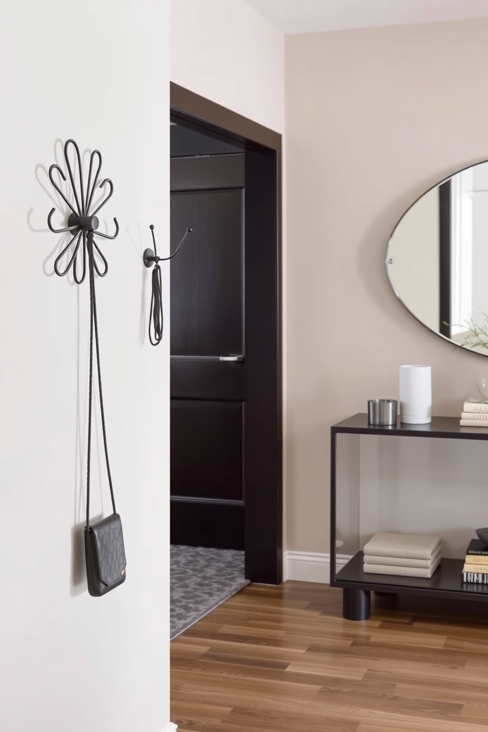 A contemporary foyer features stylish coat hooks in unique designs that serve as both functional and artistic elements. The walls are adorned with a soft neutral color, while a sleek console table sits against one side, topped with decorative items and a statement mirror above.