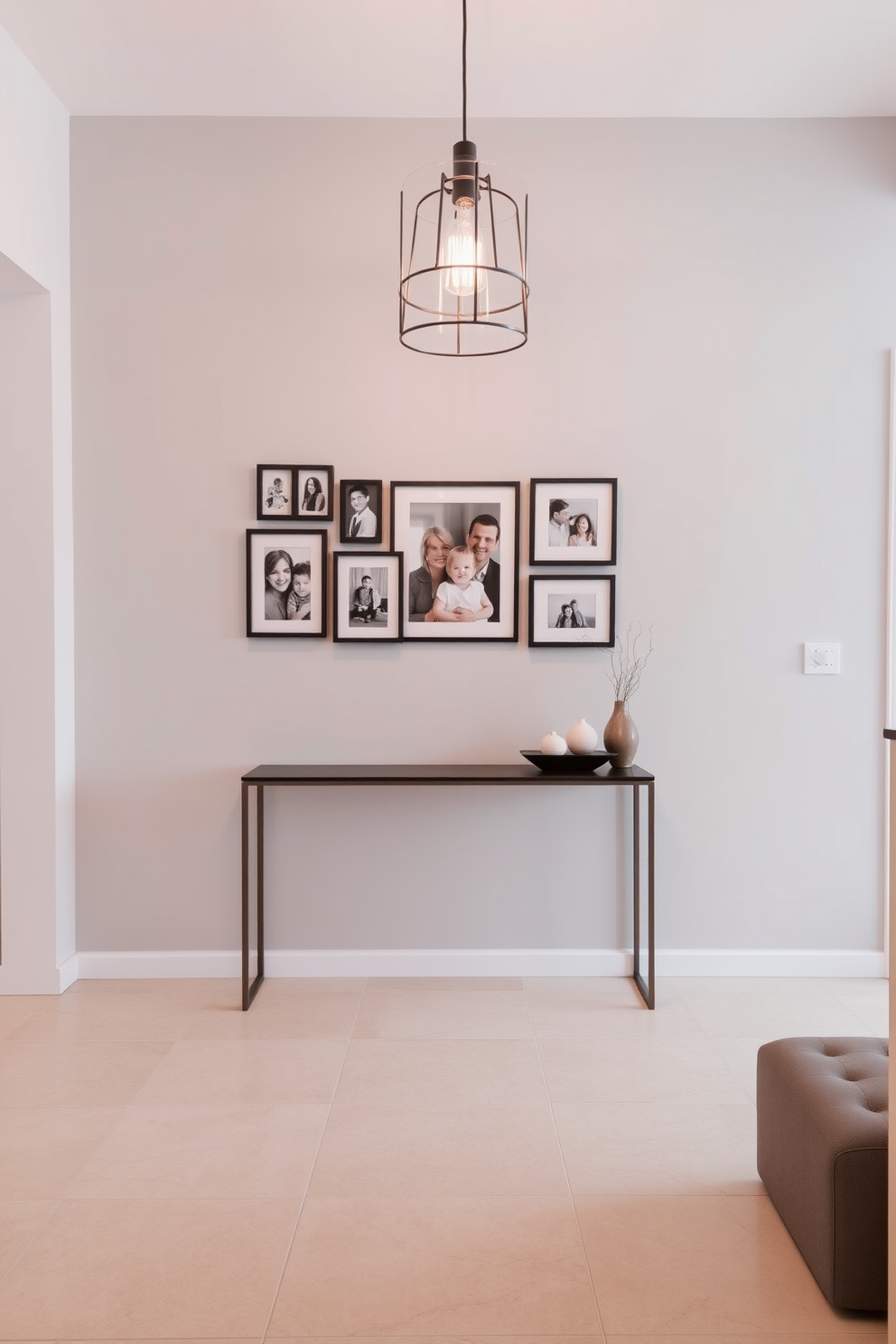 A contemporary foyer design featuring a sleek console table against a light gray wall. Framed family photos in various sizes adorn the wall above the table, adding a personal touch to the space. The floor is covered with large-format tiles in a soft beige tone, creating a warm and inviting atmosphere. A stylish pendant light hangs from the ceiling, illuminating the area and enhancing the modern aesthetic.