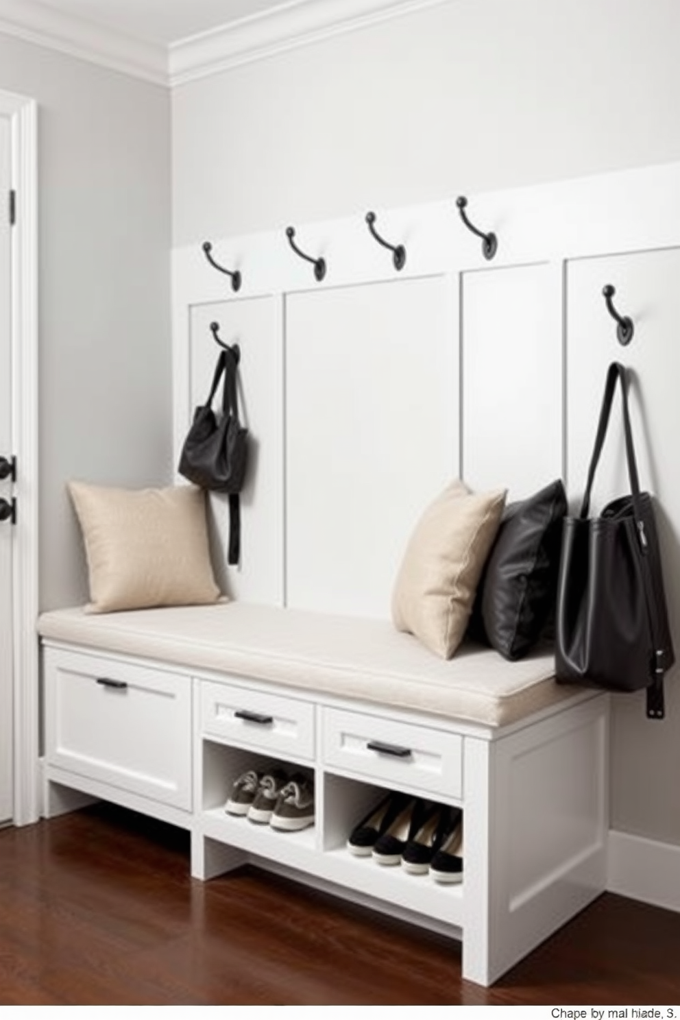 A contemporary mudroom features integrated seating that offers comfort and functionality. Beneath the seating, there is ample shoe storage with a sleek design, blending seamlessly with the overall aesthetic. The walls are adorned with a light gray paint, creating a bright and inviting atmosphere. A stylish bench with plush cushions sits against the wall, complemented by decorative hooks for coats and bags.