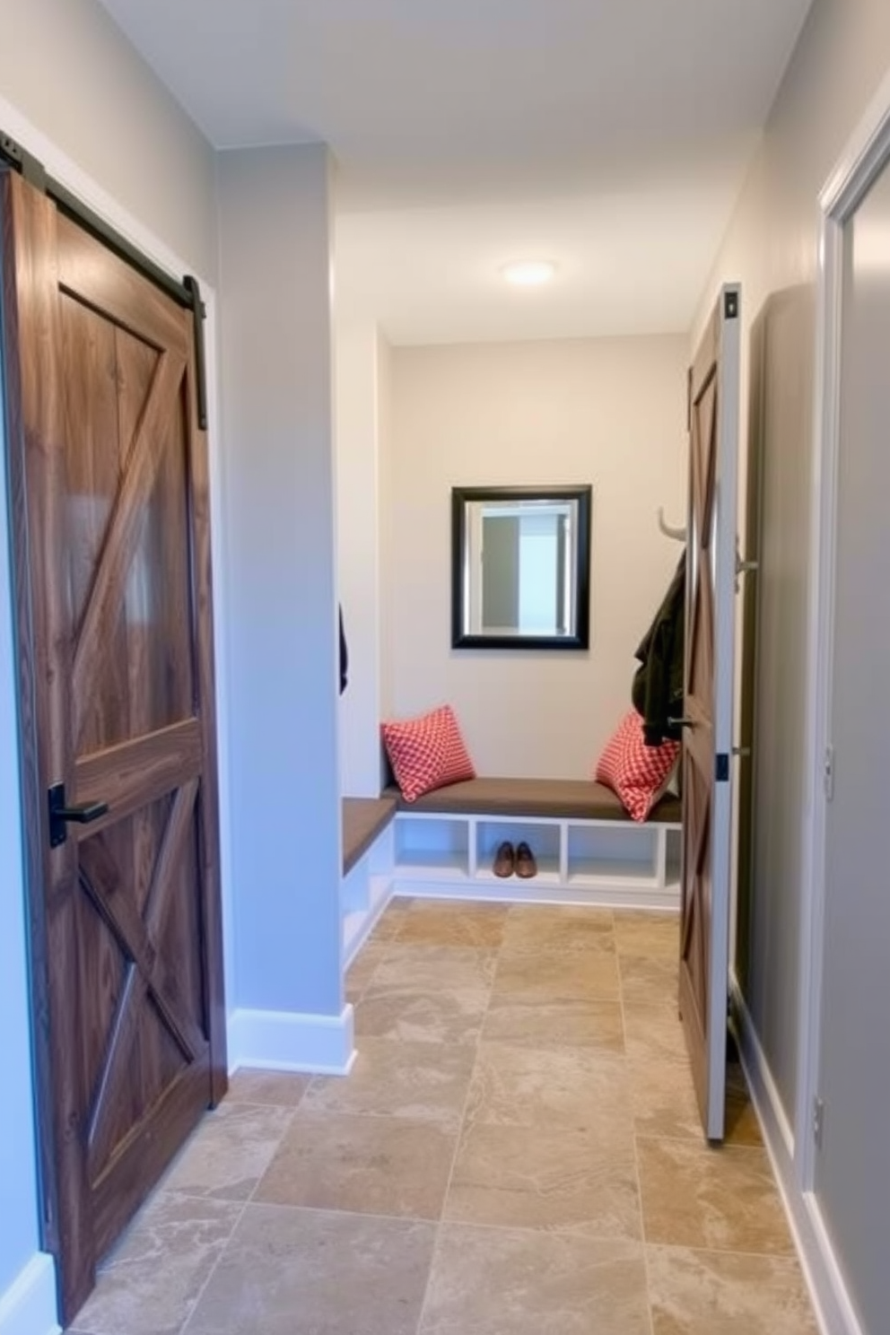 A contemporary mudroom features sliding barn doors that elegantly save space while adding a rustic charm. The walls are painted in a soft gray, and the floor is covered with durable ceramic tiles in a natural stone finish. Inside, built-in benches with storage underneath provide a practical yet stylish seating area. Hooks line the wall for hanging coats, and a large mirror enhances the sense of openness in the room.