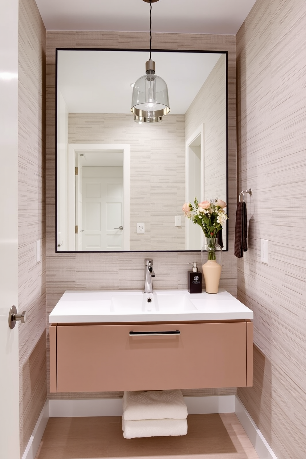 A sleek floating vanity is the focal point of this contemporary powder room. The bold mirror above the vanity adds a striking contrast, enhancing the modern aesthetic of the space. The walls are adorned with a subtle textured wallpaper that complements the vanity's clean lines. A stylish pendant light illuminates the room, creating an inviting atmosphere.