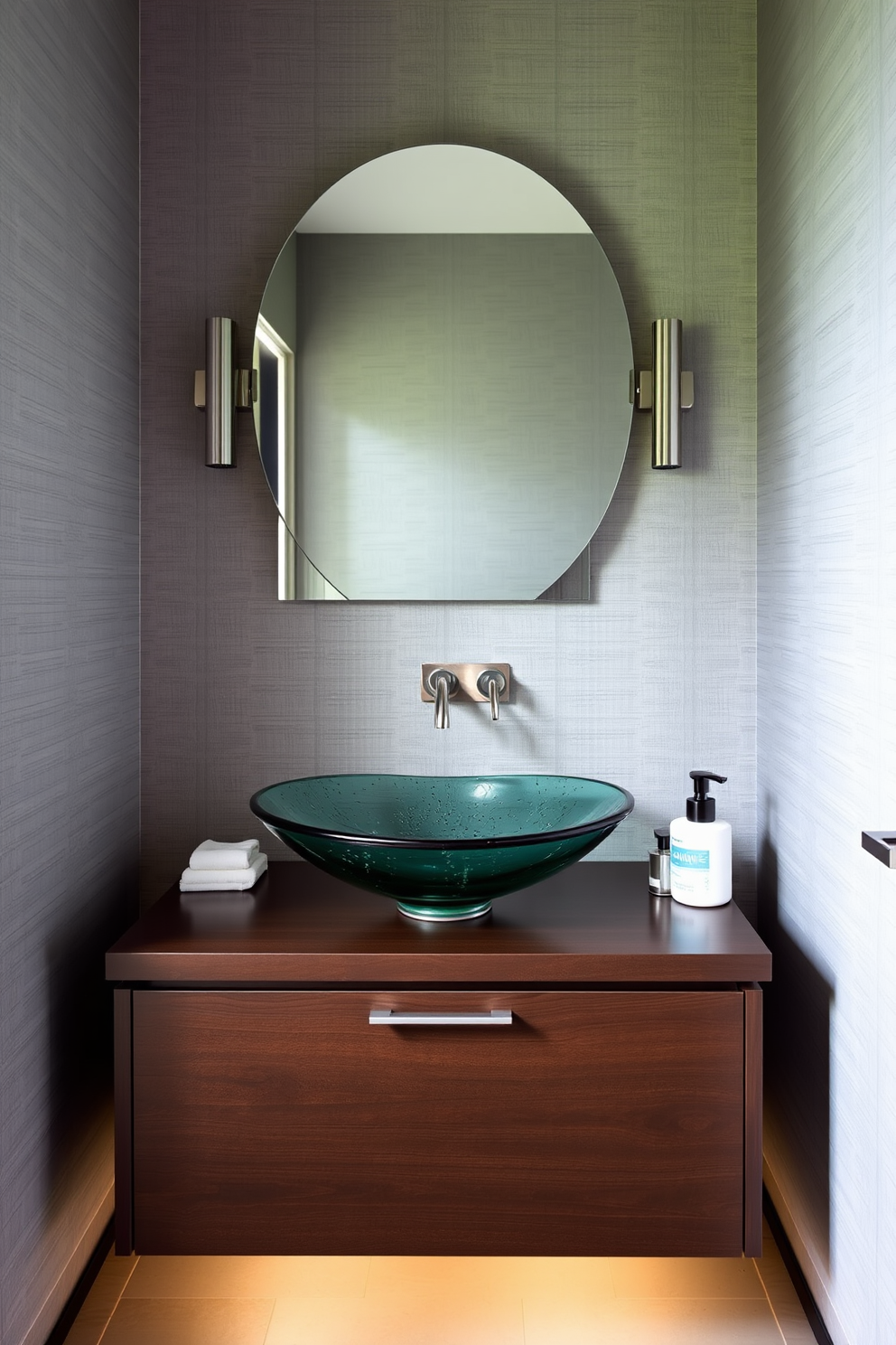 A unique vessel sink serves as the stunning centerpiece of a contemporary powder room. The sink is crafted from hand-blown glass and is complemented by sleek, modern fixtures in brushed nickel. Surrounding the sink, the walls are adorned with textured wallpaper in a soft gray hue. A minimalist floating vanity in a dark wood finish provides ample storage while enhancing the room's clean lines.