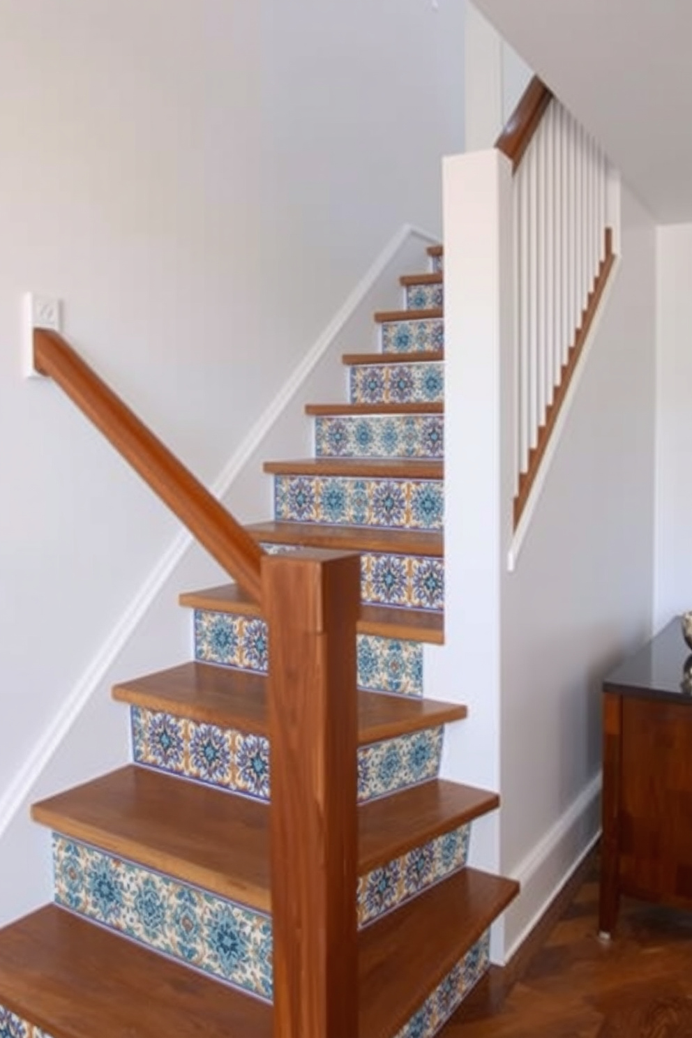 A contemporary staircase with decorative tile risers features a sleek wooden handrail and open risers that showcase intricate tile patterns. The surrounding walls are painted in a crisp white, allowing the vibrant colors of the tile to stand out beautifully.