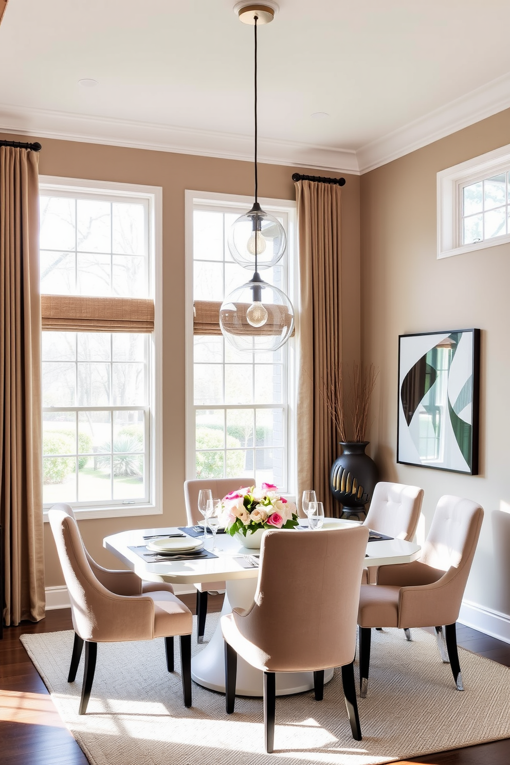 Chic pendant lights hang elegantly above a modern dining table set for six. The table is adorned with a stylish centerpiece of fresh flowers and complemented by plush upholstered chairs in a soft neutral tone. The walls are painted in a warm beige, enhancing the cozy atmosphere of the corner dining room. Large windows allow natural light to flood the space, creating an inviting and airy feel.