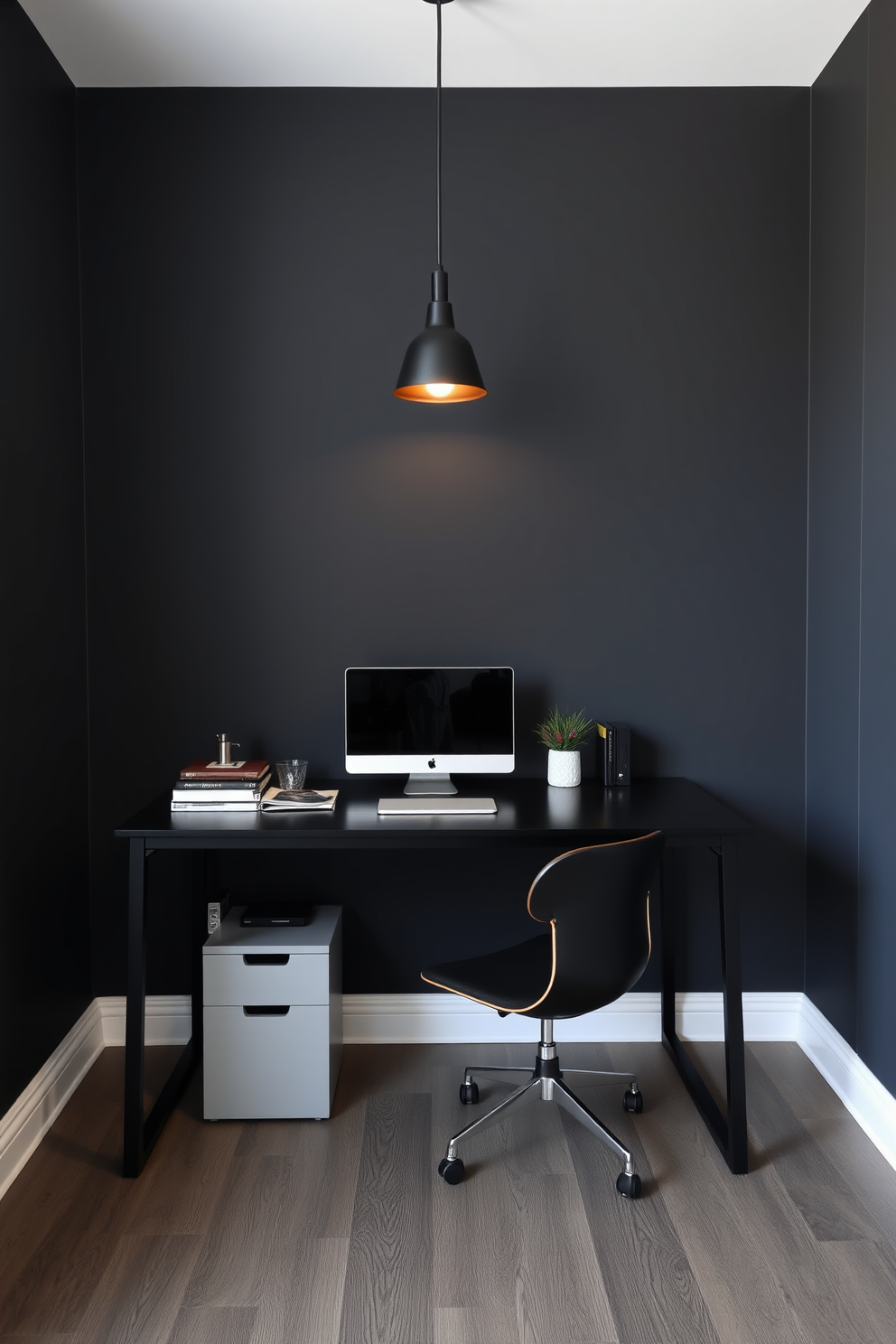 A sleek black desk sits against the wall in a dark study room, featuring minimal clutter to maintain a clean and focused environment. The walls are painted a deep charcoal gray, and a single pendant light casts a warm glow over the workspace.