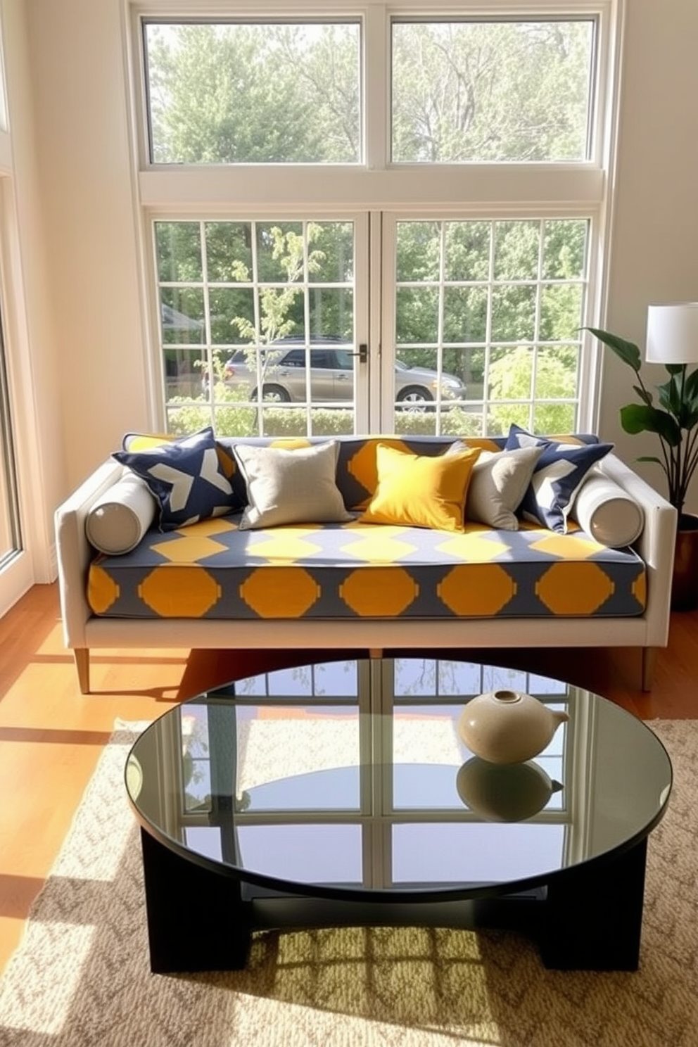 A contemporary daybed is positioned in a bright living room filled with natural light. The daybed features bold geometric patterns in shades of blue and yellow, creating a striking focal point in the space. Surrounding the daybed are plush throw pillows that complement the geometric design. A sleek coffee table made of glass and metal sits nearby, adding an element of modern elegance to the room.