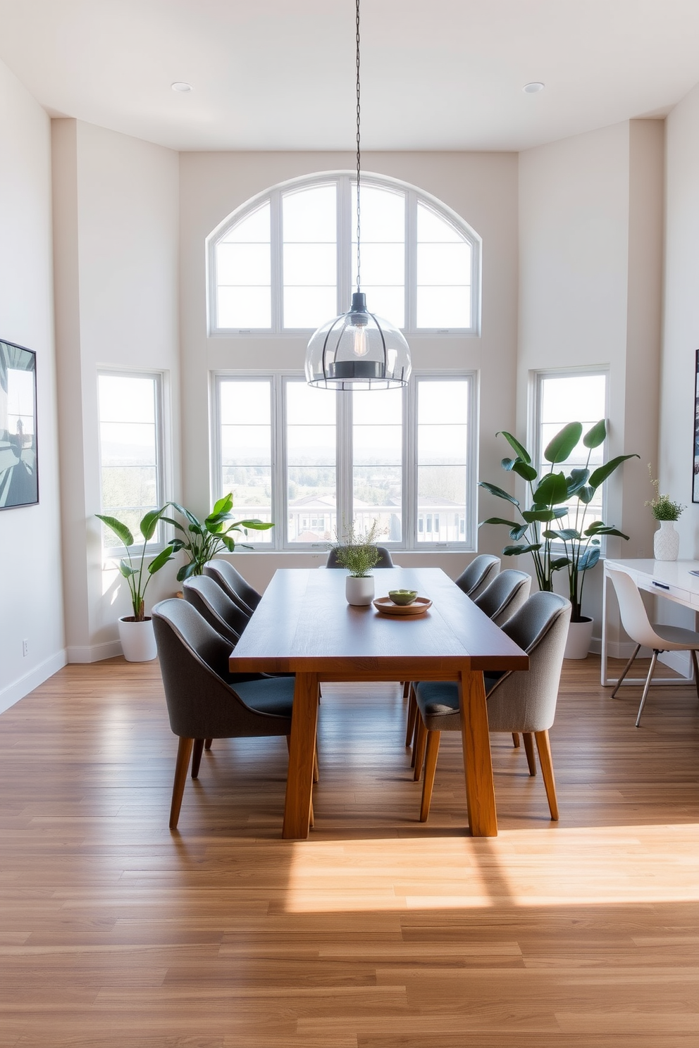 A modern dining room office combo featuring a sleek wooden dining table surrounded by comfortable upholstered chairs. Large windows allow natural light to flood the space, complemented by indoor plants placed in stylish pots to create a fresh atmosphere. On one side of the room, a minimalist desk with a contemporary chair offers a dedicated workspace. The walls are painted in a soft neutral tone, and a statement pendant light hangs above the dining table, adding elegance to the design.