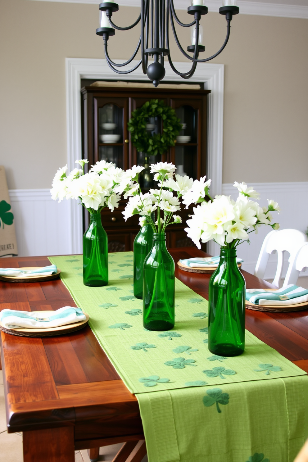 A charming dining room decorated for St. Patrick's Day features a rustic wooden table set with green glass bottles as vases. Each bottle is filled with fresh white flowers, creating a beautiful contrast against the vibrant green table runner adorned with shamrocks.