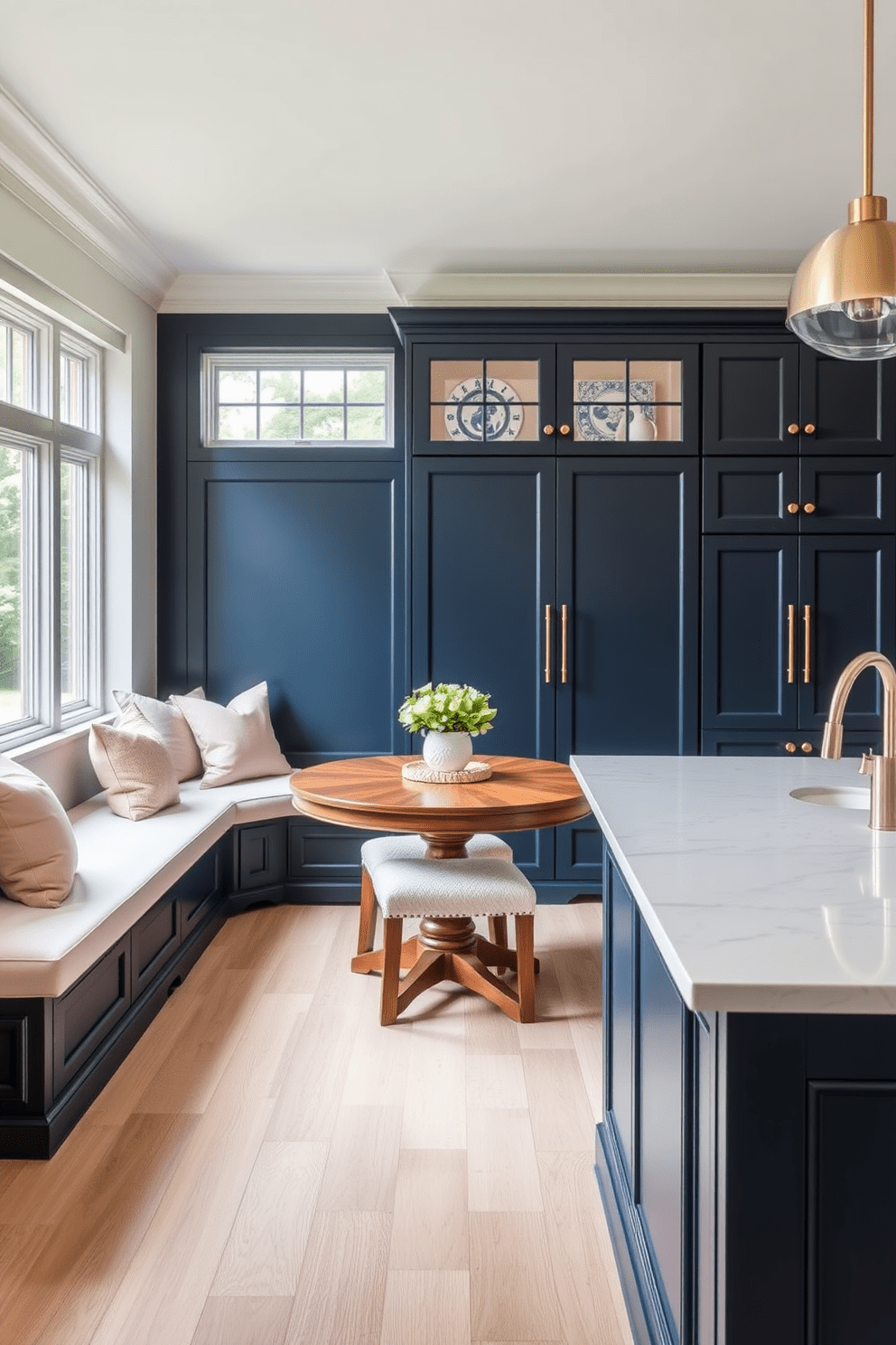 Cozy breakfast nook with built-in seating. The nook features a round wooden table surrounded by plush cushions in soft pastel colors, with large windows allowing natural light to flood the space. Elegant kitchen design ideas. The kitchen showcases sleek cabinetry in a rich navy blue, paired with gold hardware, and a large island topped with white quartz, creating a sophisticated focal point.