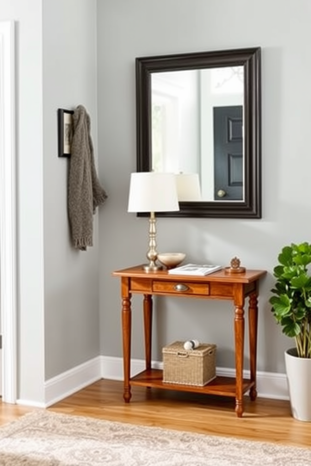 A welcoming entryway featuring a small wooden table positioned against the wall for keys and mail. The table is adorned with a stylish lamp and a decorative bowl, while a soft rug lies beneath to add warmth to the space. The walls are painted in a soft gray hue, creating a calm atmosphere. A large mirror hangs above the table, reflecting natural light and making the area feel more spacious.