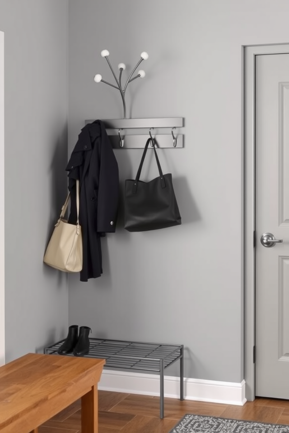 A stylish entryway features a modern coat rack made of sleek metal with a minimalist design, providing ample hanging space for coats and bags. The walls are painted in a soft gray, complemented by a warm wooden bench that invites guests to sit and remove their shoes.