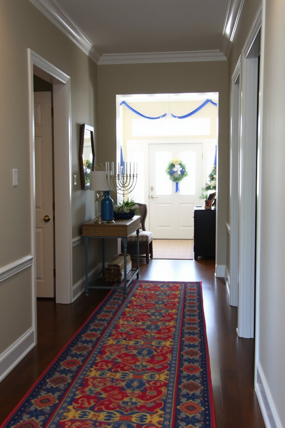 A colorful patterned runner stretches down the hallway, bringing vibrancy and warmth to the space. The runner features intricate designs in shades of blue, red, and yellow, perfectly complementing the neutral-toned walls. In the entryway, festive Hanukkah decorations adorn the space, creating a welcoming atmosphere. A beautifully arranged menorah sits on a console table, surrounded by blue and silver accents that enhance the holiday spirit.