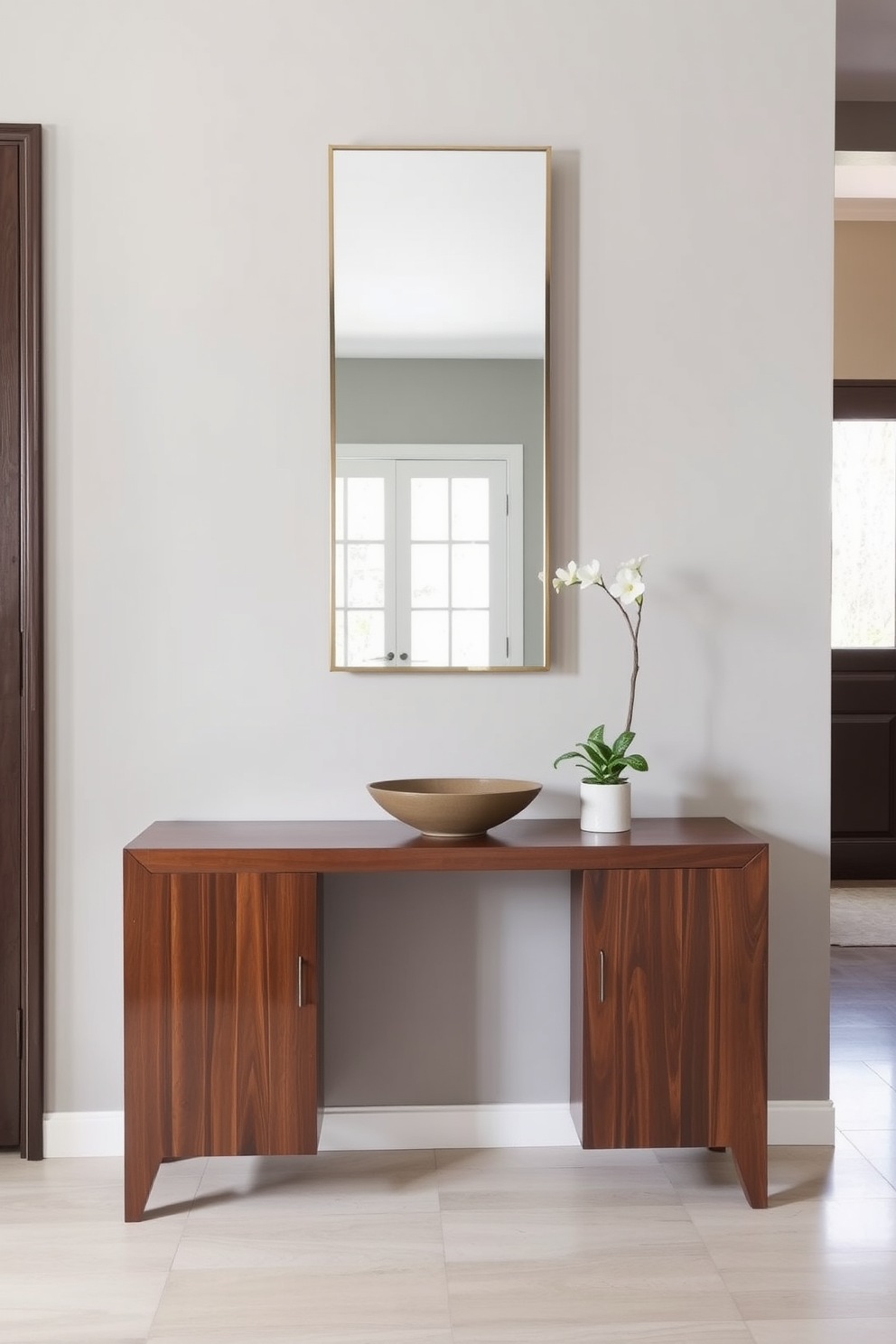 A stylish mirror hangs above a sleek entryway table crafted from dark wood. The table is adorned with a decorative bowl and a small potted plant, creating a welcoming atmosphere in the entryway.