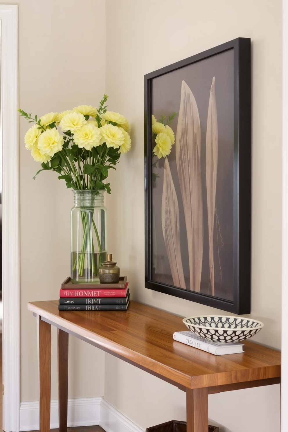 A stylish entryway featuring a wooden table with varying heights of decor items. On one side, a tall vase with fresh flowers stands beside a stack of books, while on the other, a small decorative bowl adds a touch of elegance.