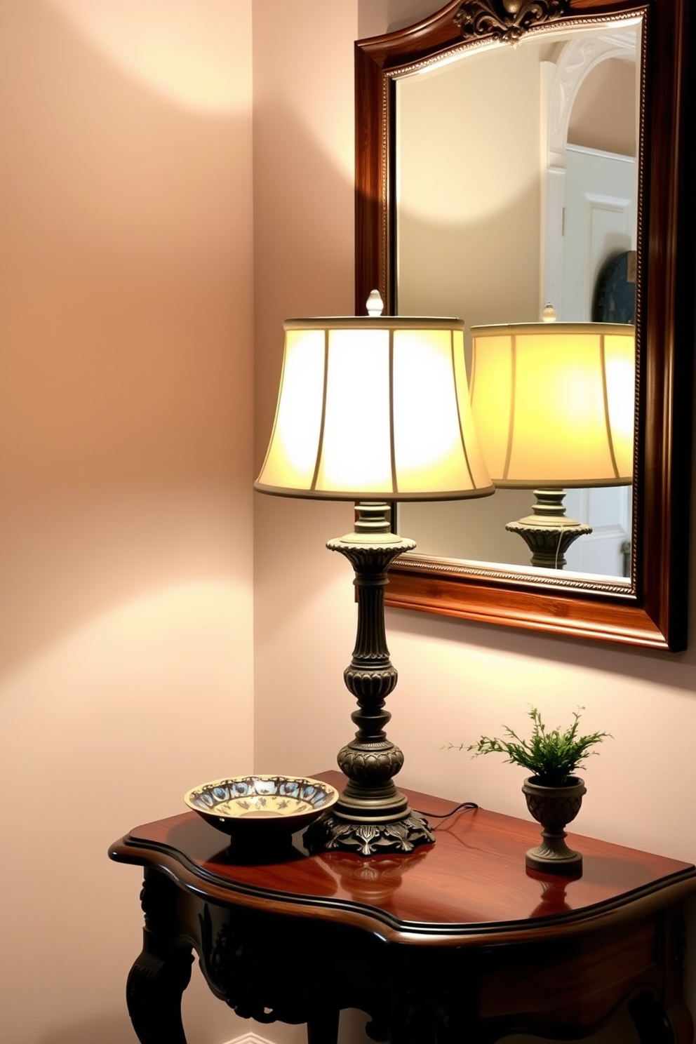 A vintage lamp with an ornate base and a soft fabric shade sits atop an elegant entryway table. The table features intricate carvings and is adorned with a decorative bowl and a small potted plant, creating a welcoming atmosphere. The lamp casts a warm glow, illuminating the rich wood tones of the table and enhancing the cozy ambiance of the entryway. A stylish mirror hangs above the table, reflecting the light and adding depth to the space.