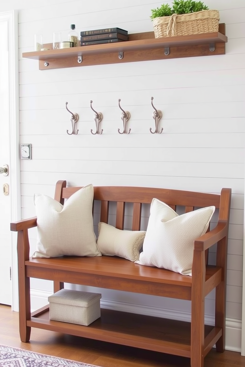 A cozy entryway featuring a small wooden bench with soft cushions. Above the bench, a series of stylish wall hooks in a brushed nickel finish are mounted on a light gray shiplap wall.