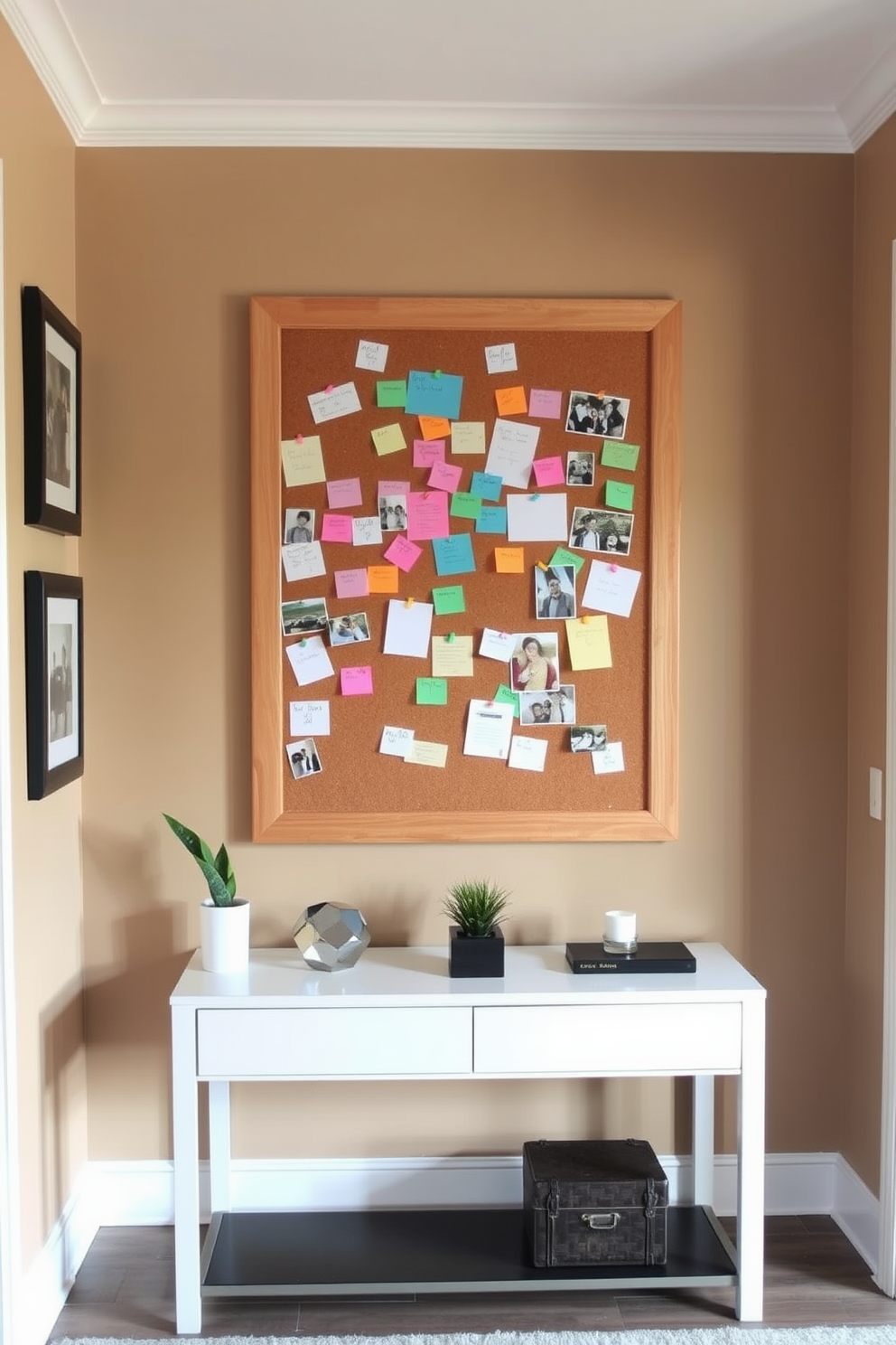 A stylish entryway featuring a large corkboard mounted on a wooden frame. The corkboard is filled with colorful notes and reminders, surrounded by a gallery of framed family photos. The wall behind the corkboard is painted in a warm neutral tone, creating a welcoming atmosphere. A sleek console table below the corkboard holds decorative items and a small potted plant for added charm.