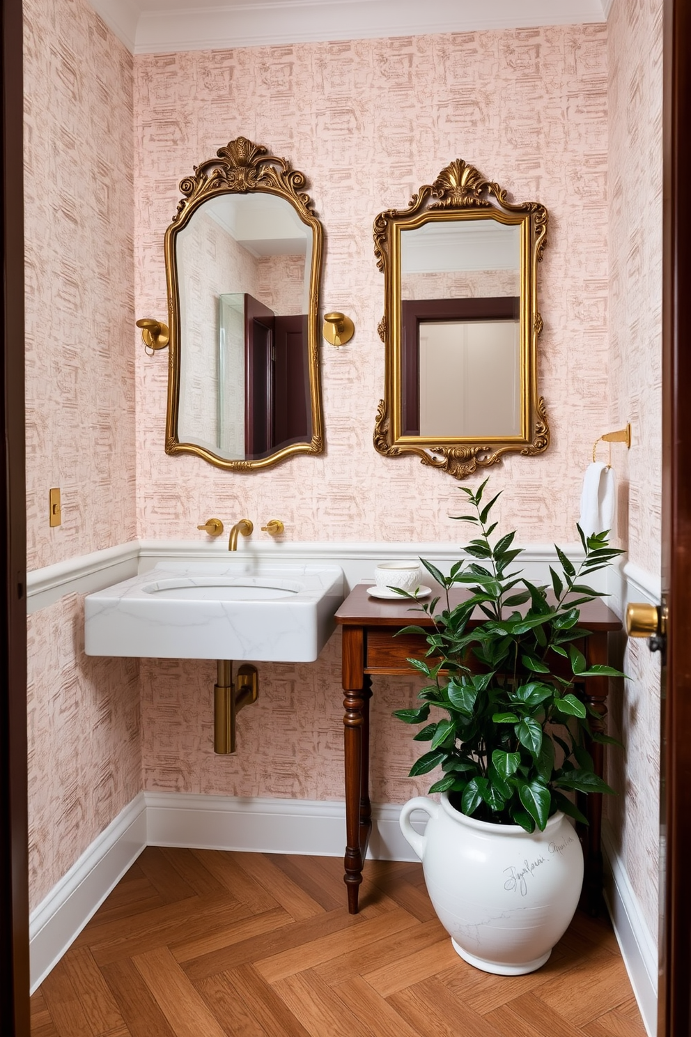 A European powder room featuring a blend of mixed materials for a layered aesthetic. The walls are adorned with textured wallpaper in soft pastels, complemented by a sleek marble sink and a wooden console table. Elegant brass fixtures add a touch of sophistication, while a vintage mirror with an ornate frame hangs above the sink. The floor is covered in herringbone-patterned wood, and lush greenery in a ceramic pot brings life to the space.