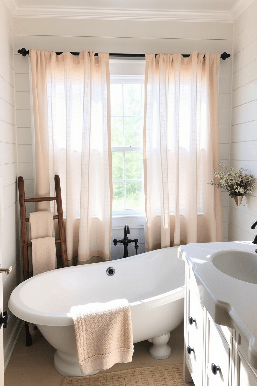 A charming farmhouse bathroom featuring soft linen curtains that gently filter natural light. The space includes a freestanding soaking tub with a rustic wooden ladder beside it, adorned with plush towels. The walls are painted in a warm white shade, complemented by shiplap accents. A vintage-style vanity with a distressed finish and a farmhouse sink adds character to the room.