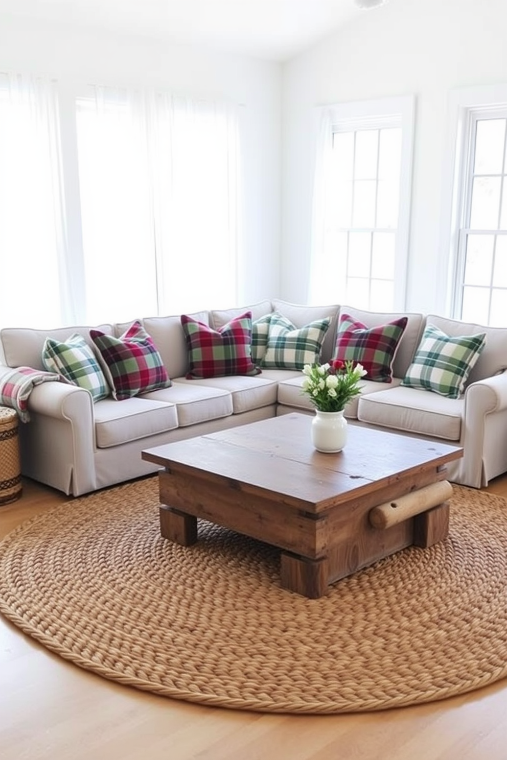 A cozy sectional sofa is adorned with plaid throw pillows in various shades of red and green. A rustic coffee table made of reclaimed wood sits in front, surrounded by a woven area rug that adds warmth to the space. The walls are painted in a soft white, creating a bright and inviting atmosphere. Large windows with sheer curtains allow natural light to flood in, enhancing the farmhouse charm of the living room.