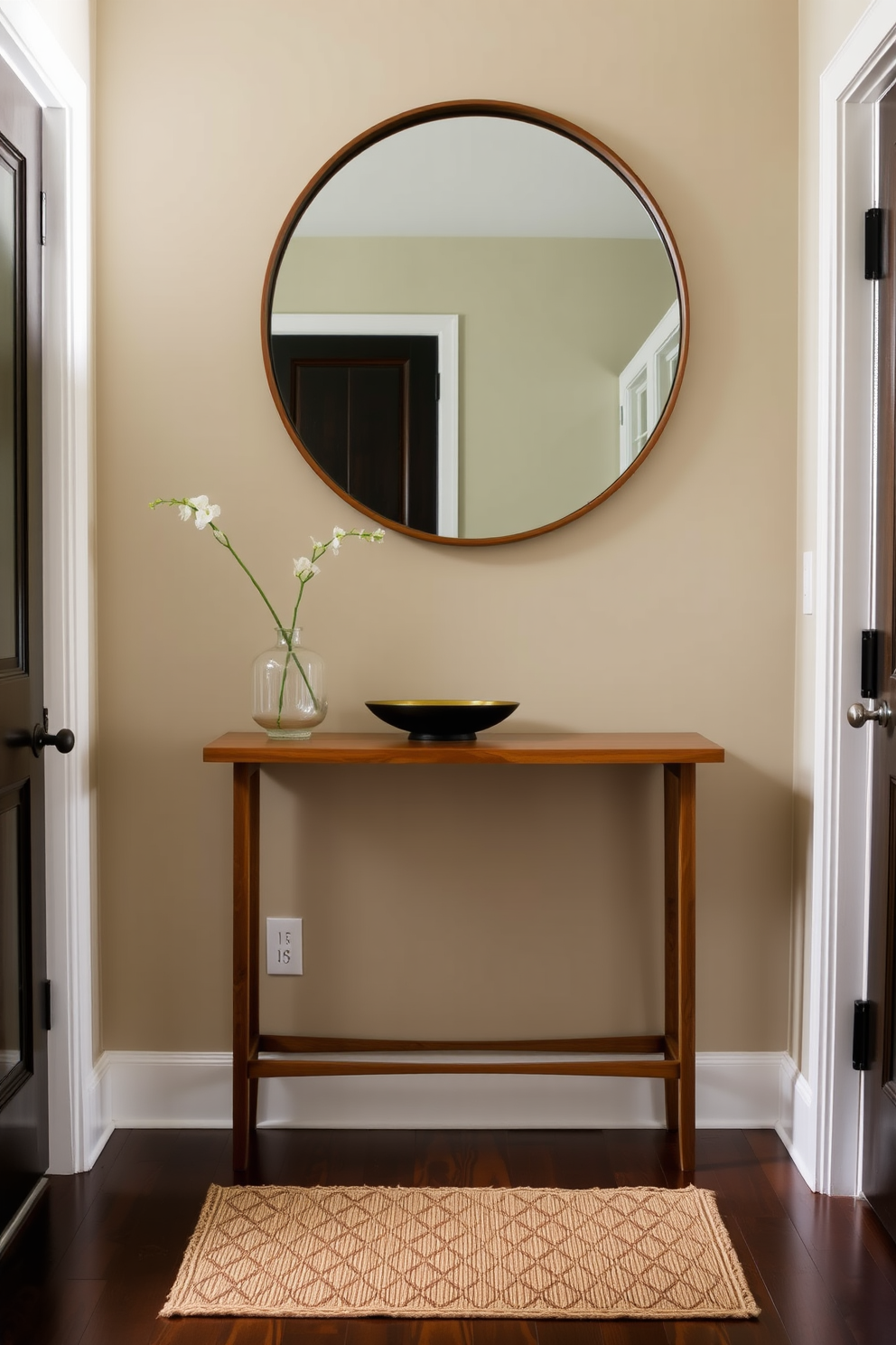 A stylish foyer featuring a warm wooden console table against the wall. Above the table, a large round mirror reflects natural light, while a chic welcome mat lies at the entrance, inviting guests into the space.