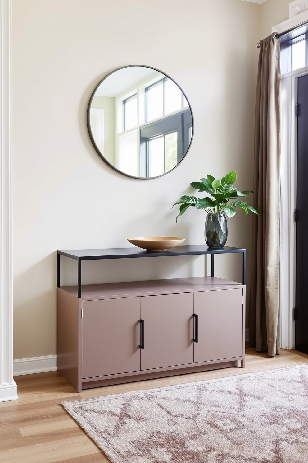 A stylish foyer featuring a sleek console table with ample storage space underneath. The walls are adorned with a soft beige paint, while a large round mirror hangs above the table, reflecting natural light from a nearby window. On the console table, a decorative bowl and a small potted plant add a touch of elegance. A cozy area rug in muted tones anchors the space, providing warmth and texture to the entryway.