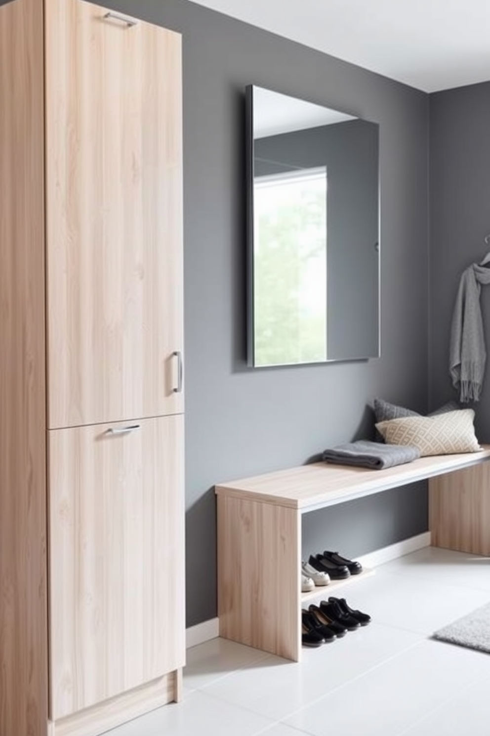 A sleek shoe cabinet stands against the wall in a modern entryway, designed to keep shoes organized and out of sight. The cabinet features a smooth finish in a light wood tone, complemented by minimalist metal handles for a clean look. Adjacent to the shoe cabinet, a stylish bench provides a comfortable spot for putting on or taking off shoes. The walls are painted in a soft gray, while a large mirror above the bench enhances the sense of space and light.