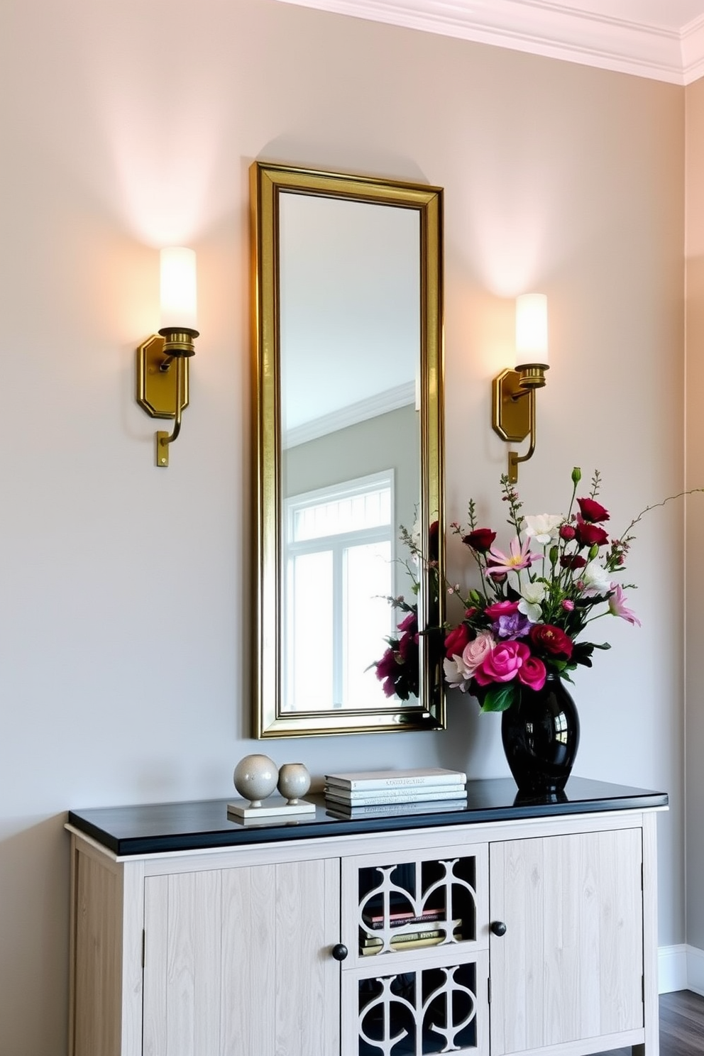 A welcoming foyer entryway features layered lighting with elegant sconces flanking a tall mirror. A stylish console table sits against the wall, adorned with decorative objects and a vibrant floral arrangement.