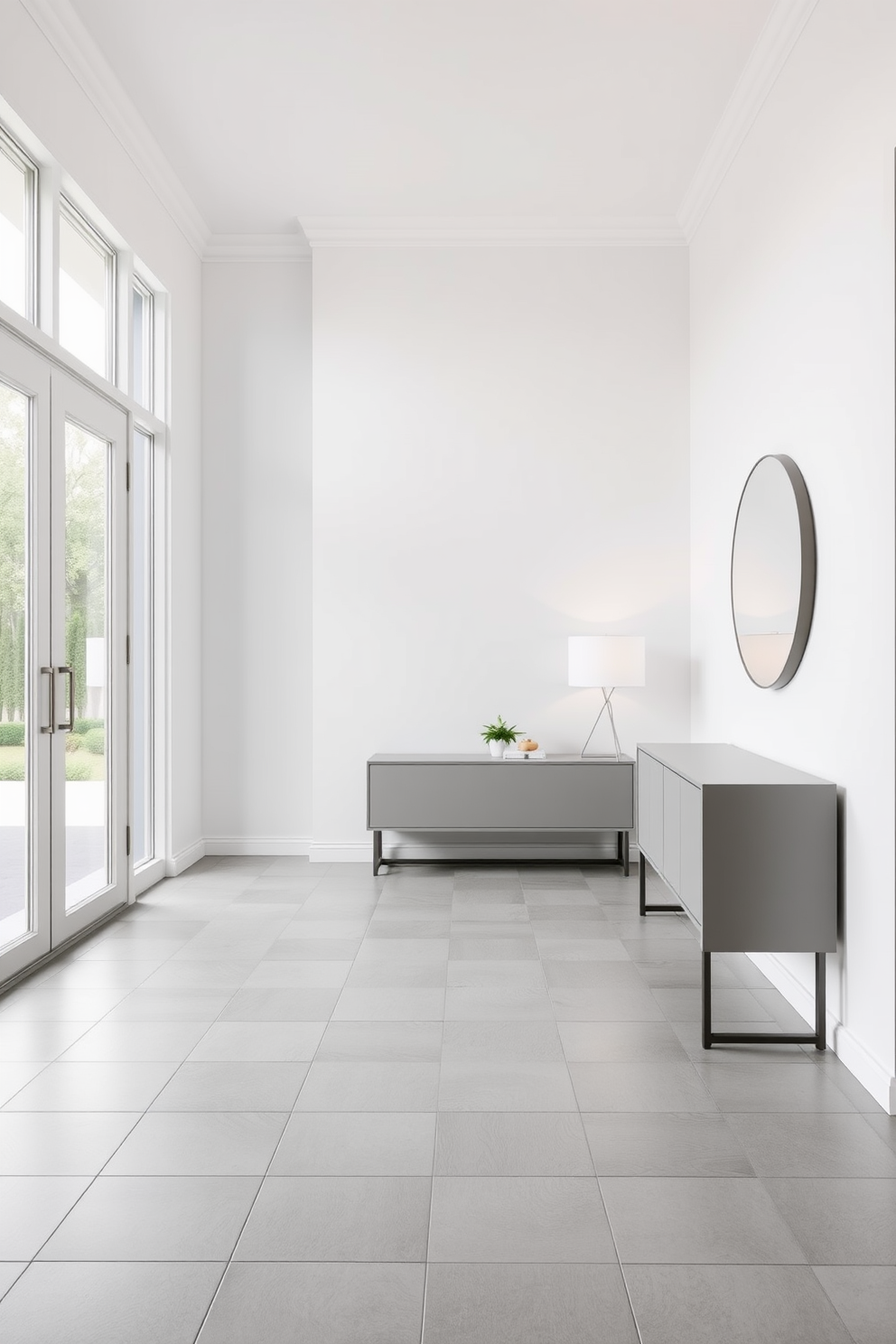 A spacious foyer with minimalist tiles that create a clean and inviting atmosphere. The tiles are laid in a simple grid pattern, featuring soft gray tones that enhance the natural light streaming in from large windows. A sleek console table is positioned against the wall, adorned with a small potted plant and a minimalist lamp. The walls are painted in a crisp white, complementing the understated elegance of the tile design.