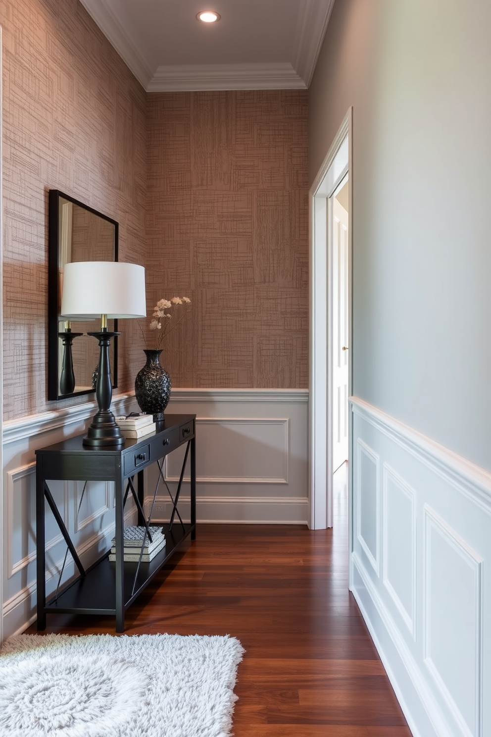 A stunning foyer featuring layered textures that create depth and dimension. The walls are adorned with a combination of wainscoting and textured wallpaper, enhancing the visual interest of the space. A stylish console table sits against the wall, topped with decorative accents like a chic lamp and a sculptural vase. The floor is finished with rich hardwood, complemented by a plush area rug that adds warmth and comfort to the entrance.