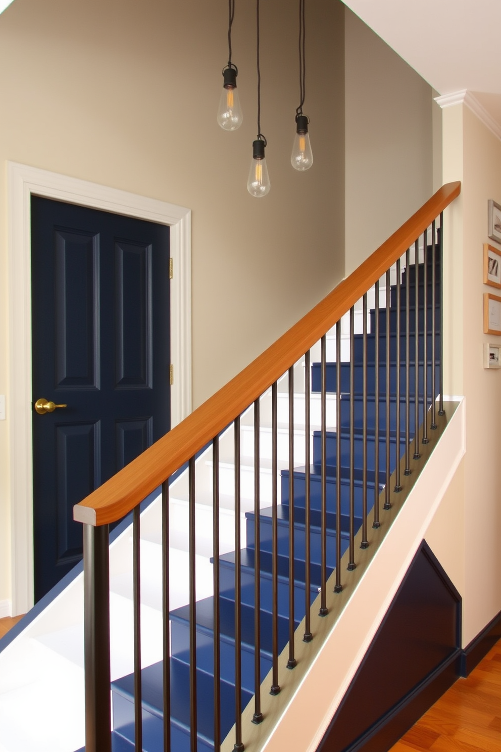 A stylish staircase featuring a sleek wooden handrail and contrasting metal balusters creates a striking visual impact. The steps are painted in a deep navy blue, while the risers are adorned with a crisp white finish, adding a modern touch to the overall design. The staircase is illuminated by a series of pendant lights that hang gracefully from the ceiling above. A small gallery wall showcasing framed artwork lines the adjacent wall, enhancing the aesthetic appeal of this functional space.