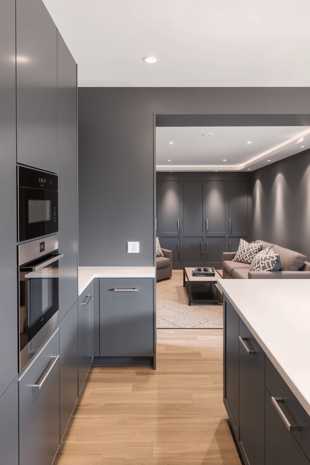 A sleek gray kitchenette features modern appliances seamlessly integrated into the cabinetry. The countertops are a polished white quartz, providing a striking contrast against the gray tones of the kitchen. In the adjacent gray basement, the design incorporates cozy seating with plush sofas and a contemporary coffee table. Soft lighting fixtures enhance the ambiance, creating an inviting and functional space for relaxation and entertainment.