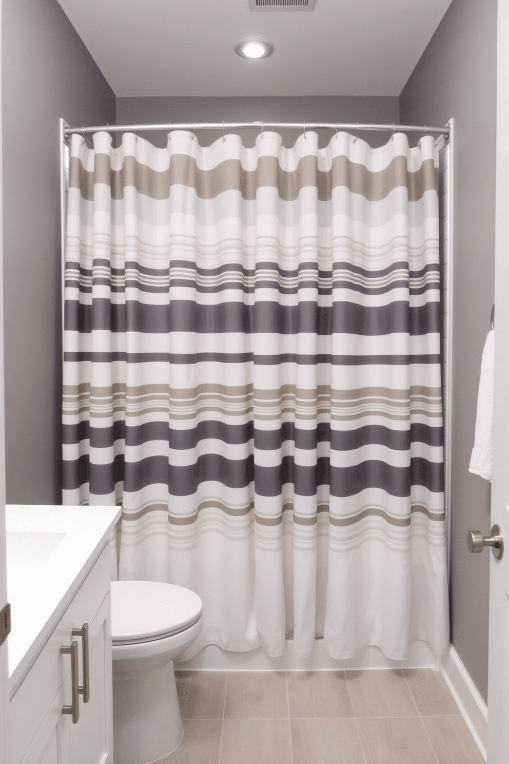 A modern gray bathroom featuring a gray and white striped shower curtain that adds texture and interest. The walls are painted in a soft gray hue, complemented by sleek white cabinetry and brushed nickel fixtures.