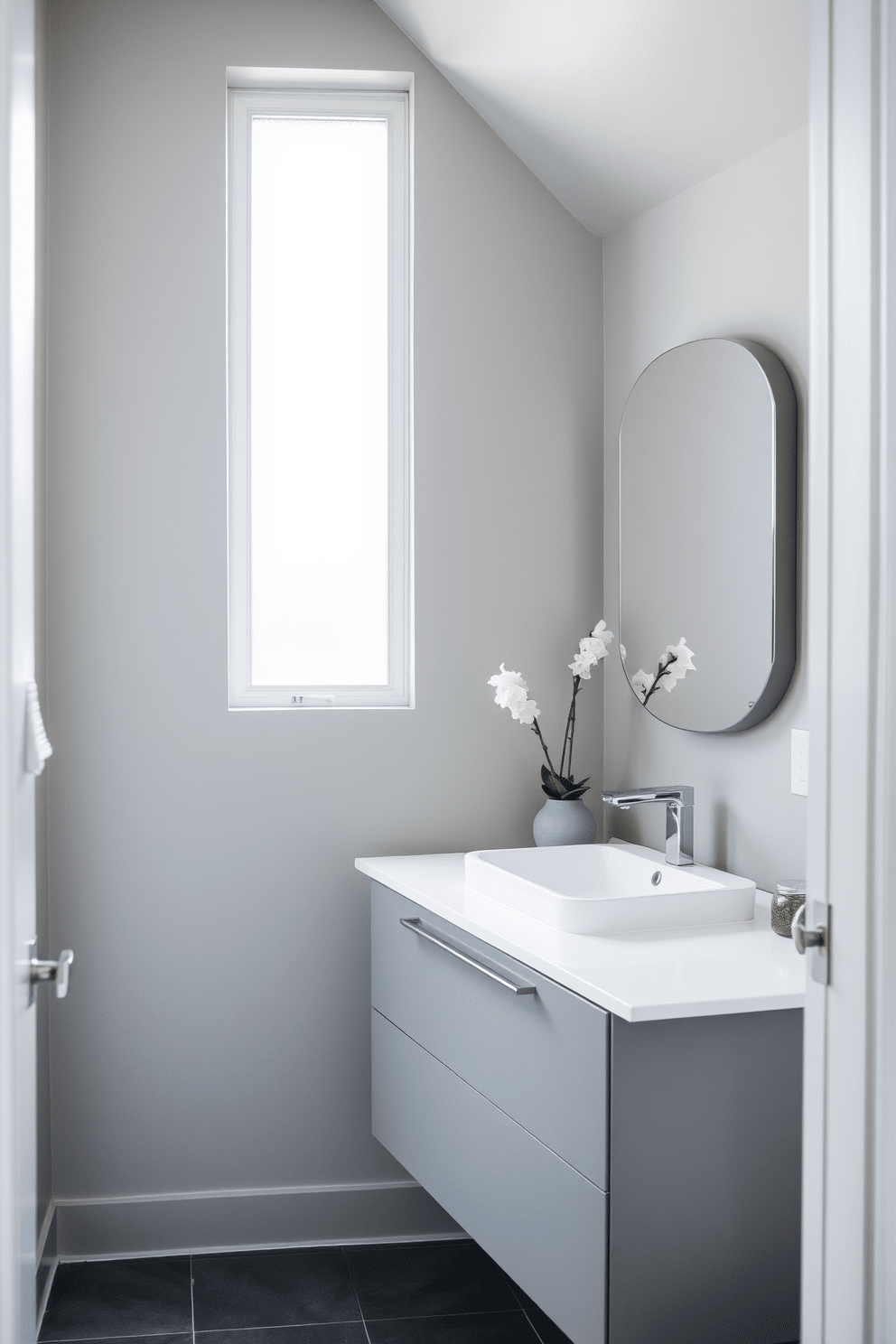 A serene bathroom space featuring a neutral gray color palette that promotes calmness. The walls are painted in a soft gray, complemented by a sleek gray vanity with a white countertop and a modern sink. Natural light floods the room through a frosted glass window, enhancing the tranquil atmosphere. Accents of darker gray in the tile flooring and accessories create depth and sophistication.