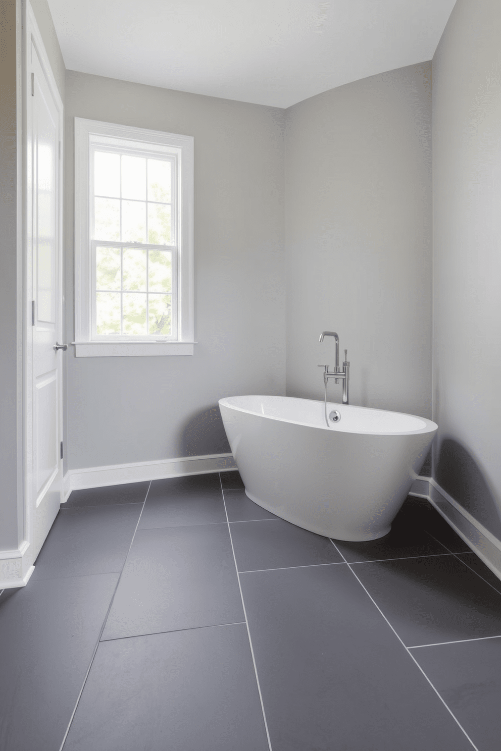 A sleek bathroom featuring charcoal gray floor tiles complemented by crisp white grout. The walls are adorned with soft gray paint, creating a serene and modern atmosphere. Minimalist fixtures in brushed nickel enhance the contemporary feel of the space. A freestanding tub sits elegantly in the corner, surrounded by natural light from a nearby window.