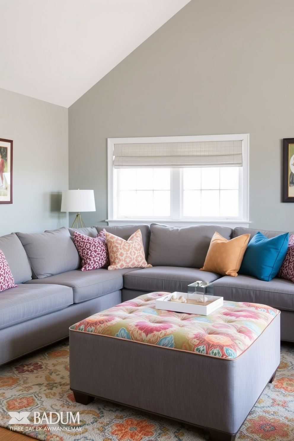 A cozy family room featuring a gray ottoman upholstered in colorful patterned fabric. The walls are painted in a soft gray hue, complemented by a plush sectional sofa adorned with vibrant throw pillows.