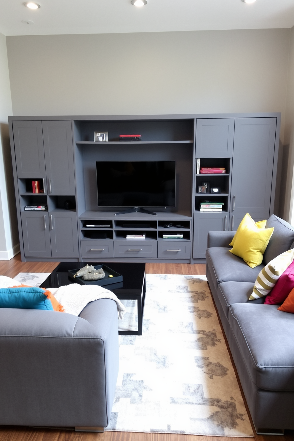 A modern gray entertainment center with a sleek design serves as the focal point of the family room. The center features open shelving and closed cabinetry, providing ample storage while maintaining a clean aesthetic. The family room is adorned with a plush gray sectional sofa, complemented by colorful throw pillows for a pop of color. A large area rug anchors the seating arrangement, creating a cozy and inviting atmosphere.