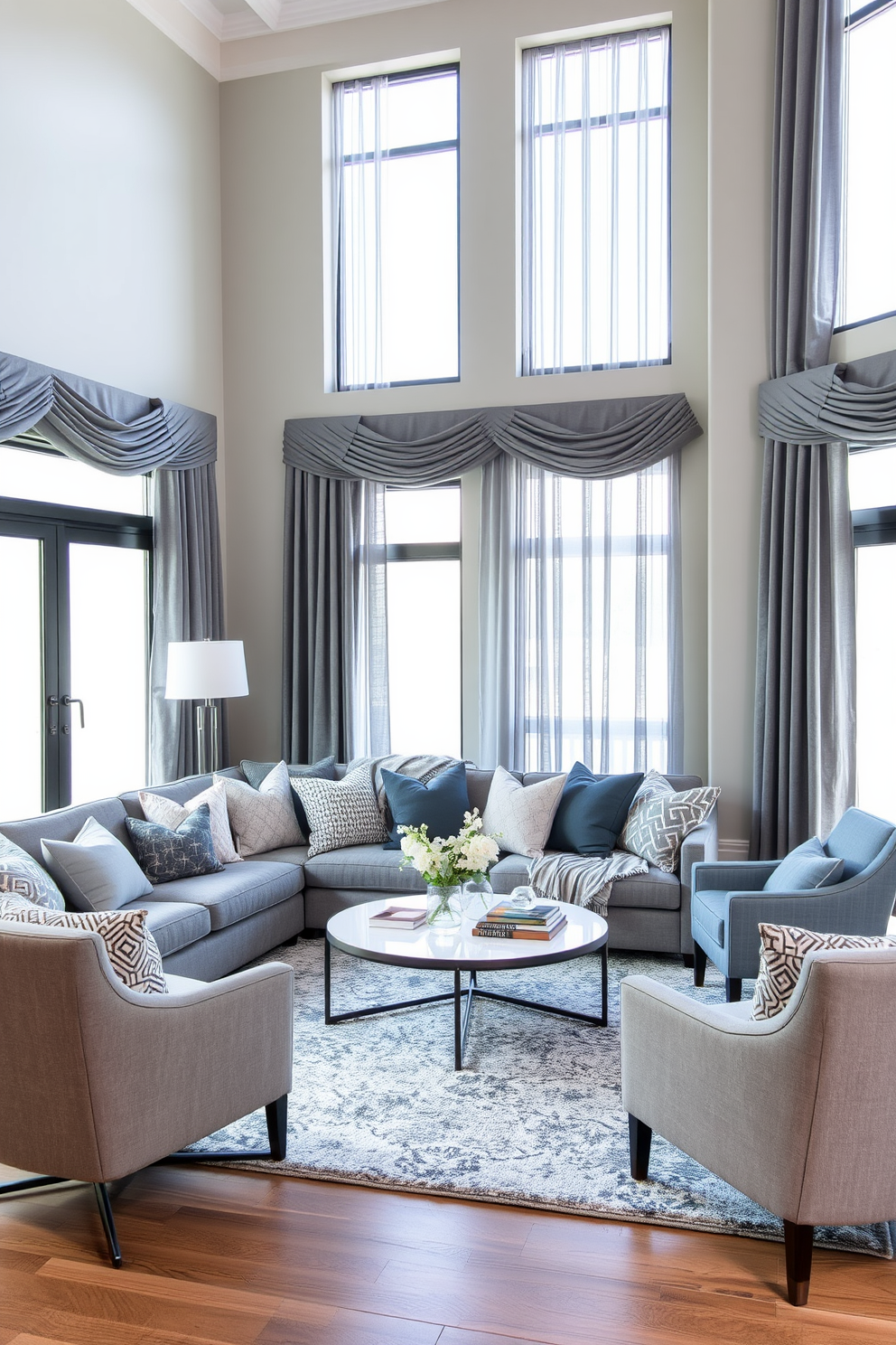 A cozy family room featuring a mix of gray fabrics to create visual interest. The space includes a plush gray sectional sofa adorned with various textured throw pillows and a soft gray area rug underfoot. Large windows allow natural light to flood the room, highlighting the layered gray curtains that drape elegantly. A modern coffee table sits at the center, surrounded by stylish accent chairs in complementary shades of gray.