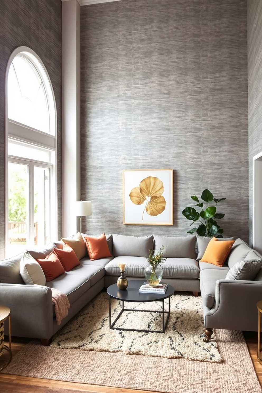 A cozy family room featuring textured gray wallpaper that adds depth and warmth to the space. The room is furnished with a plush sectional sofa in a complementary shade, accented by colorful throw pillows. Natural light floods in through large windows, enhancing the inviting atmosphere. A stylish coffee table sits at the center, surrounded by a soft area rug that ties the design together.